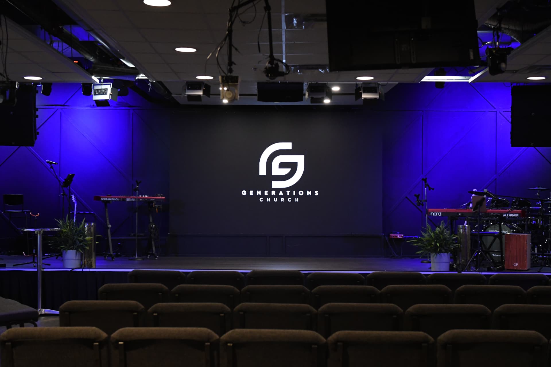 The Generations Church auditorium with our logo lit on the stage wall