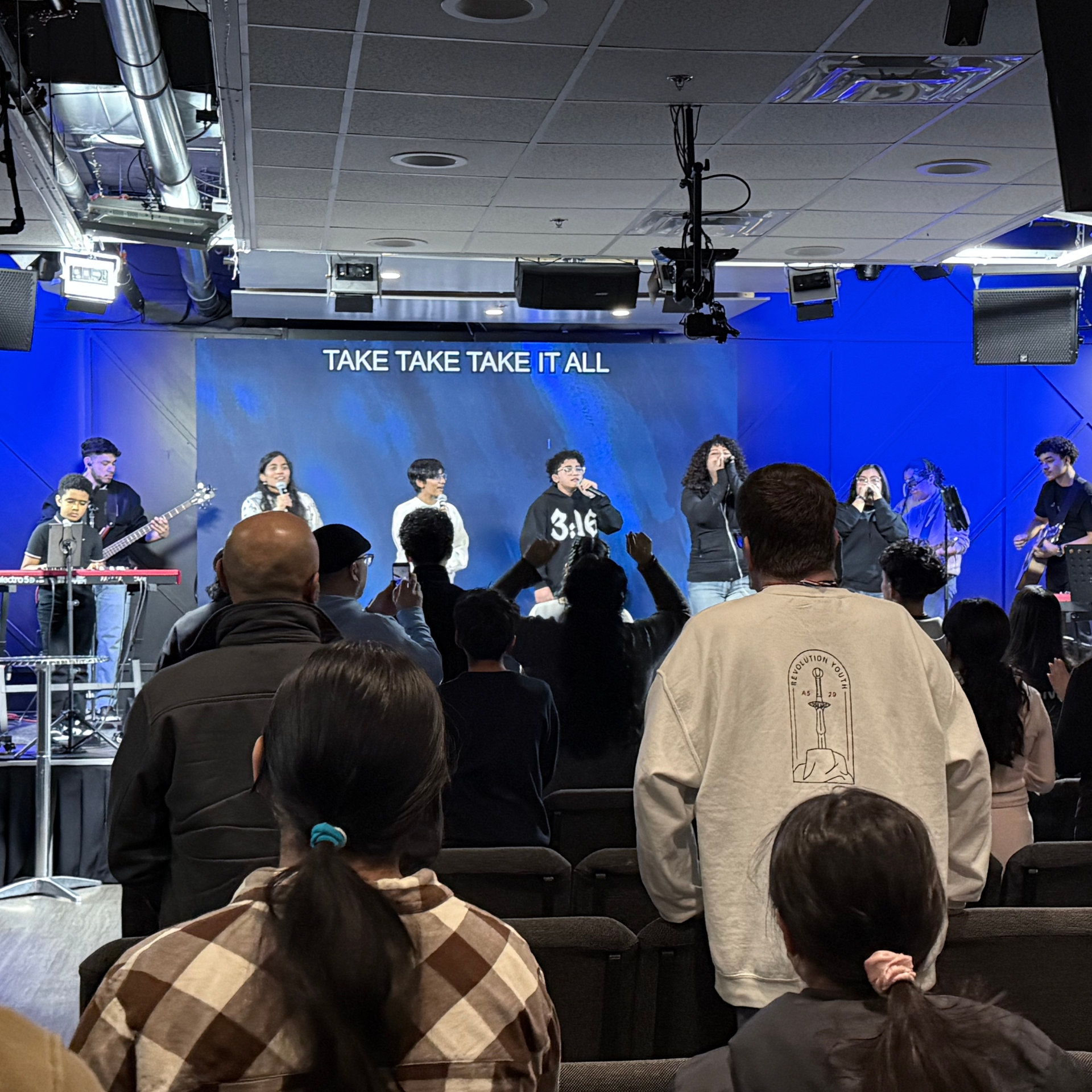 Youth worship team leading the room with hands raised