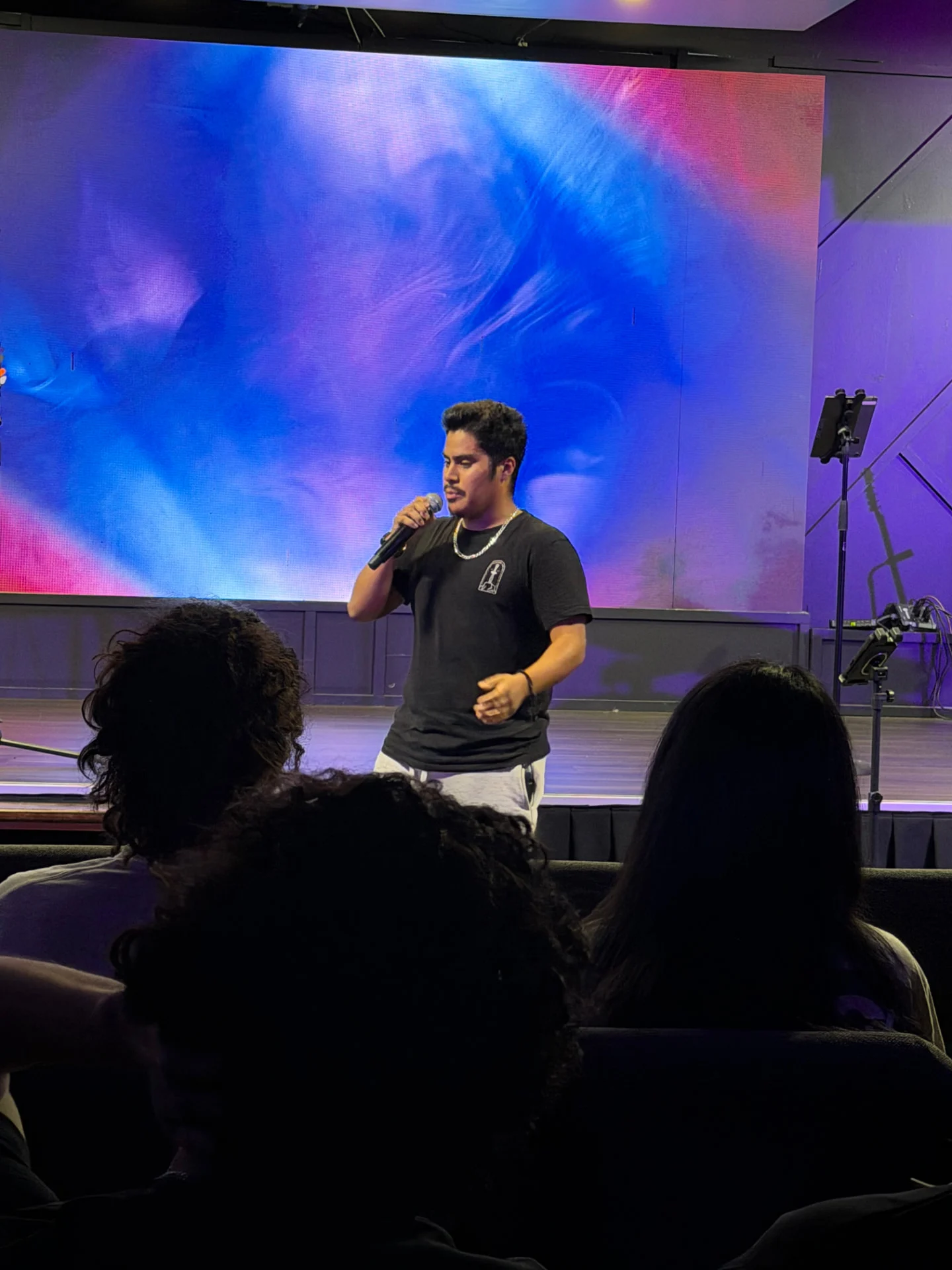 A young adult sharing on stage at a Glory Nights gathering