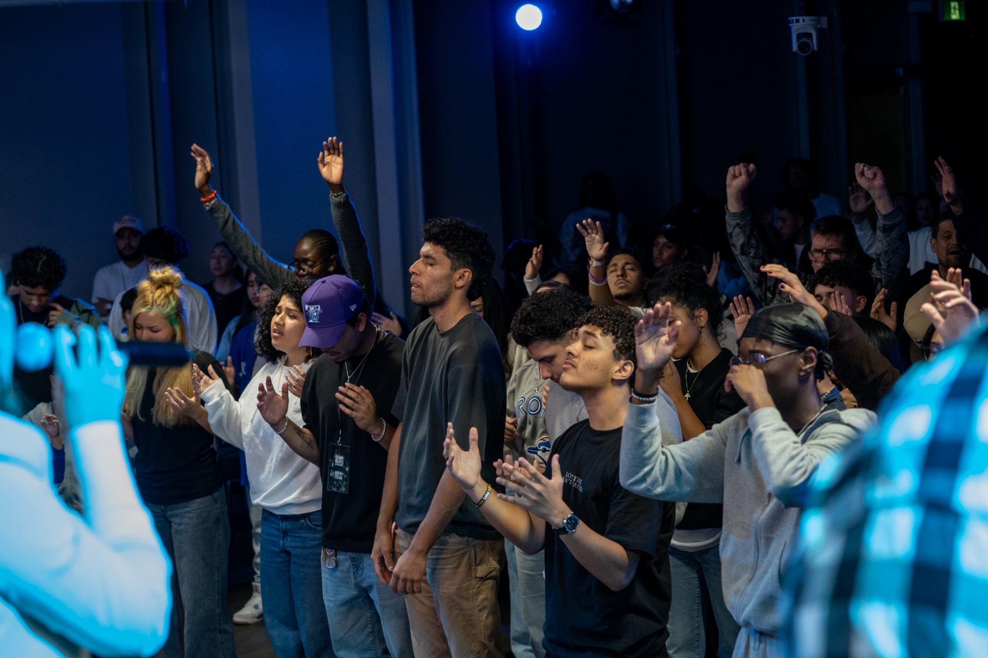 Crowd with raised hands worshipping at a Worship Nights gathering